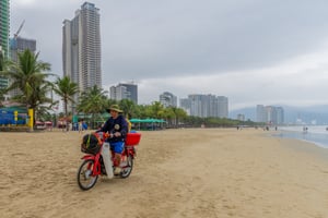 Lái xe máy mua bán hàng trên bờ biển