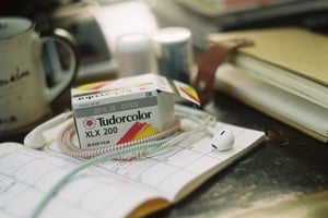 Vintage Tudorcolor film roll box on a planner notebook with wired earphones