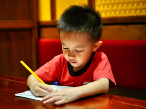 Một cậu bé đang viết trên giấy