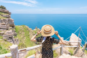 A girl in black dress holding straw hat