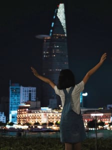 A little girl is cheering on a background of Ho Chi Minh City and Bitexco Tower