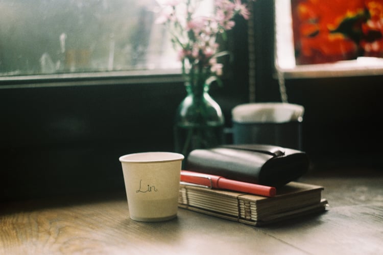 Moody retro workspace with a personal journal, pink fountain pen, and wildflower vase