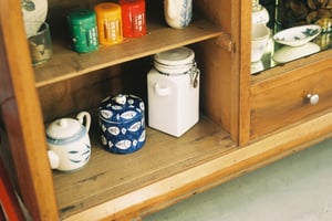 Vintage wooden cabinet shelf with traditional ceramic teapots and colorful tea tins