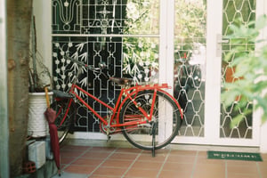 Chiếc xe đạp cổ màu đỏ dựng trước hiên nhà cửa sắt hoa văn vintage