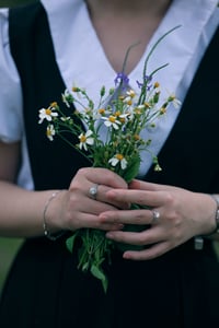 Một cô gái đang cầm bó hoa cúc dại