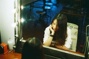 Thoughtful young woman looking at her reflection in a vintage mirror