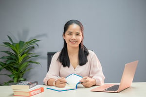 Cô gái mỉm cười khi đang viết