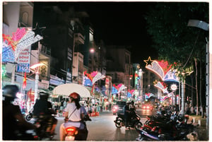 Busy city street at night with neon decorations and people riding motorbikes