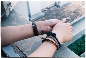Portrait of hands with small wrist tattoo and handmade accessories on a  balcony