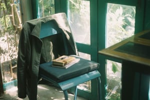 Cozy workspace corner with a jacket on a blue chair, notebook, and pen by the sunlit window