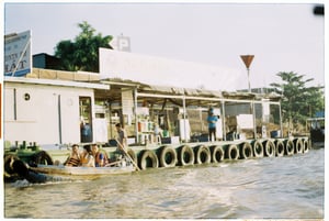 Unique floating gas station on the river with tourists in a boat, Mekong Delta, Vietnam