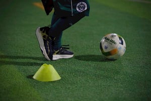 A kid dribbling the ball through obstacle