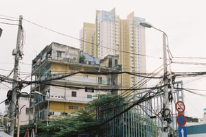 An old residential apartment with tangled messy power lines against a modern high apartment
