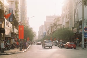 Sunlit city street in Vietnam with traffic and national flags