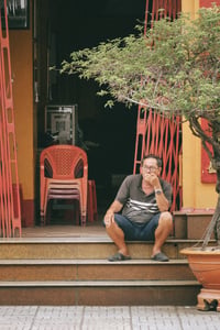 Người đàn ông hút thuốc trước cửa nhà