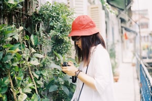 Young Asian female in a red bucket hat holding a camera