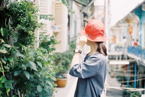 Cô gái đội mũ đỏ đứng bên ban công chung cư cổ kính ngắm nhìn phố thị