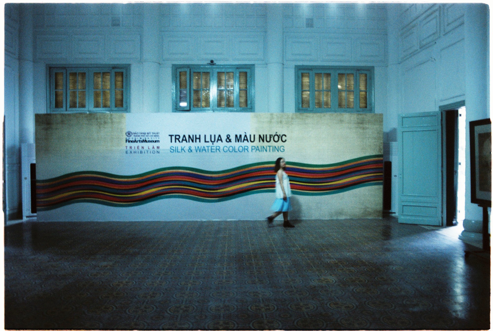 A woman walking past a big banner at the exhibition in an art museum