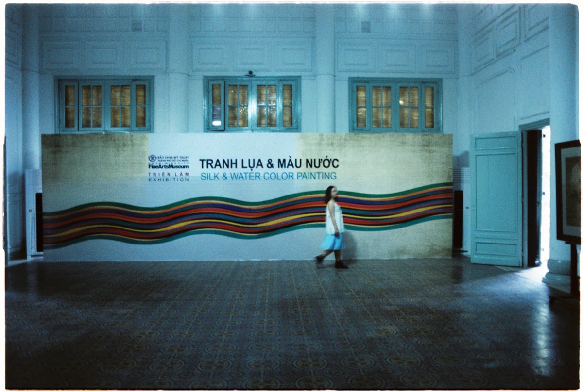 A woman walking past a big banner at the exhibition in an art museum