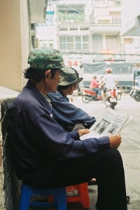 Người đàn ông lớn tuổi ngồi đọc báo