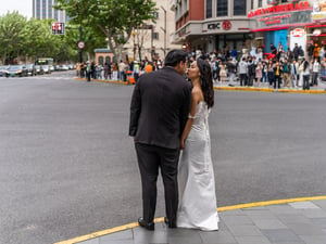 A newly-wed couple kissing on the street