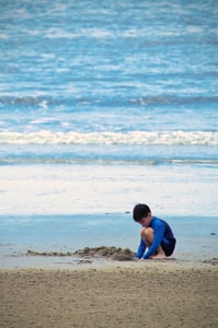 A kid playing with sand on the beach
