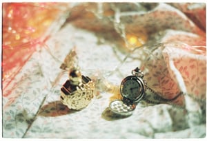 Close-up of an antique silver pocket watch on a textbook under dramatic fairy lighting