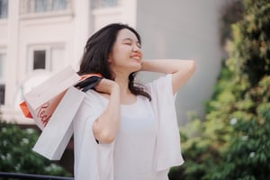 Smiling woman holding over the shoulder some shopping bags