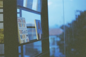 Books displayed on a glass window shelf at twilight