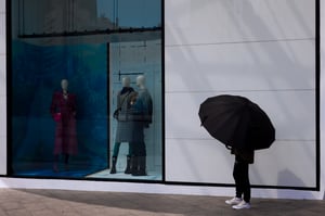 Man with umbrella standing outside a fashion store