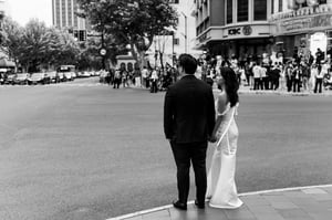 A newly-wed couple holding hands at the intersection