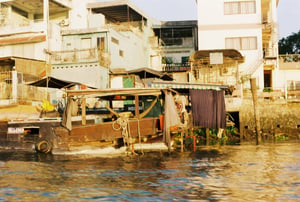 Traditional wooden boat docked by the riverside houses in Mekong Delta, Vietnam