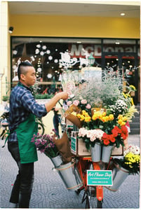 Man standing next to a bicycle full of flowers
