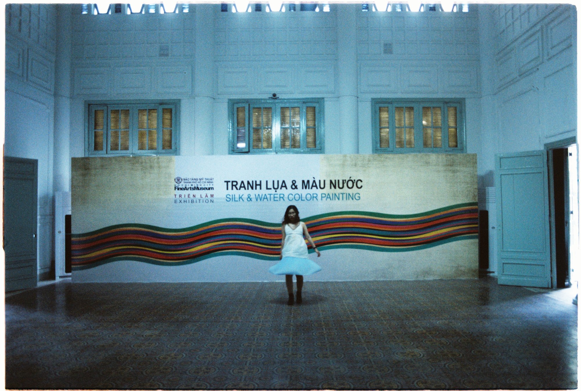 A woman walking past a big banner at the exhibition in an art museum