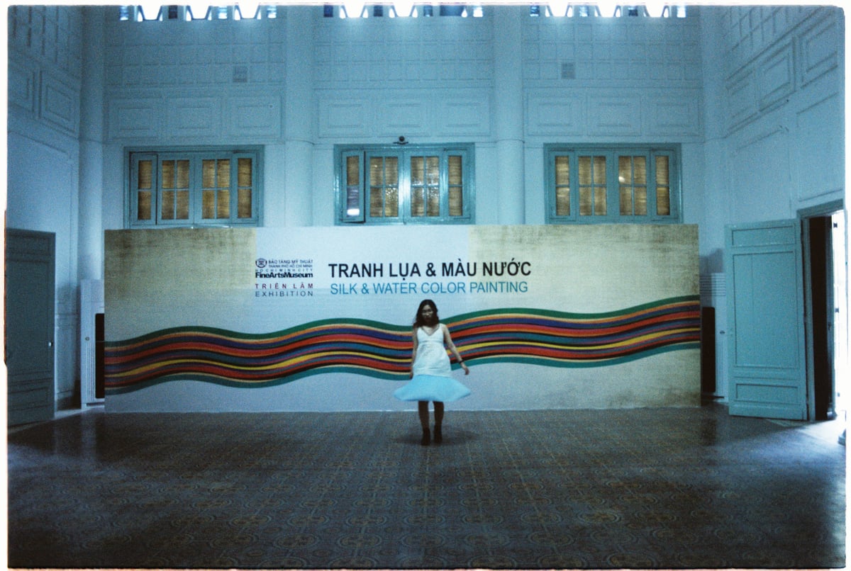 A woman walking past a big banner at the exhibition in an art museum