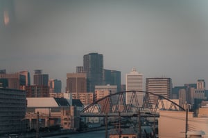 Modern city skyline with steel arch bridge and skyscrapers at sunset