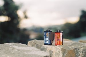 Two vintage film rolls sitting on a rustic stone ledge