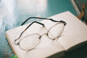 Vintage eyeglasses on an open notebook with handwritten letter